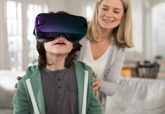 Image of young child wearing a VR headset with mother standing behind.
