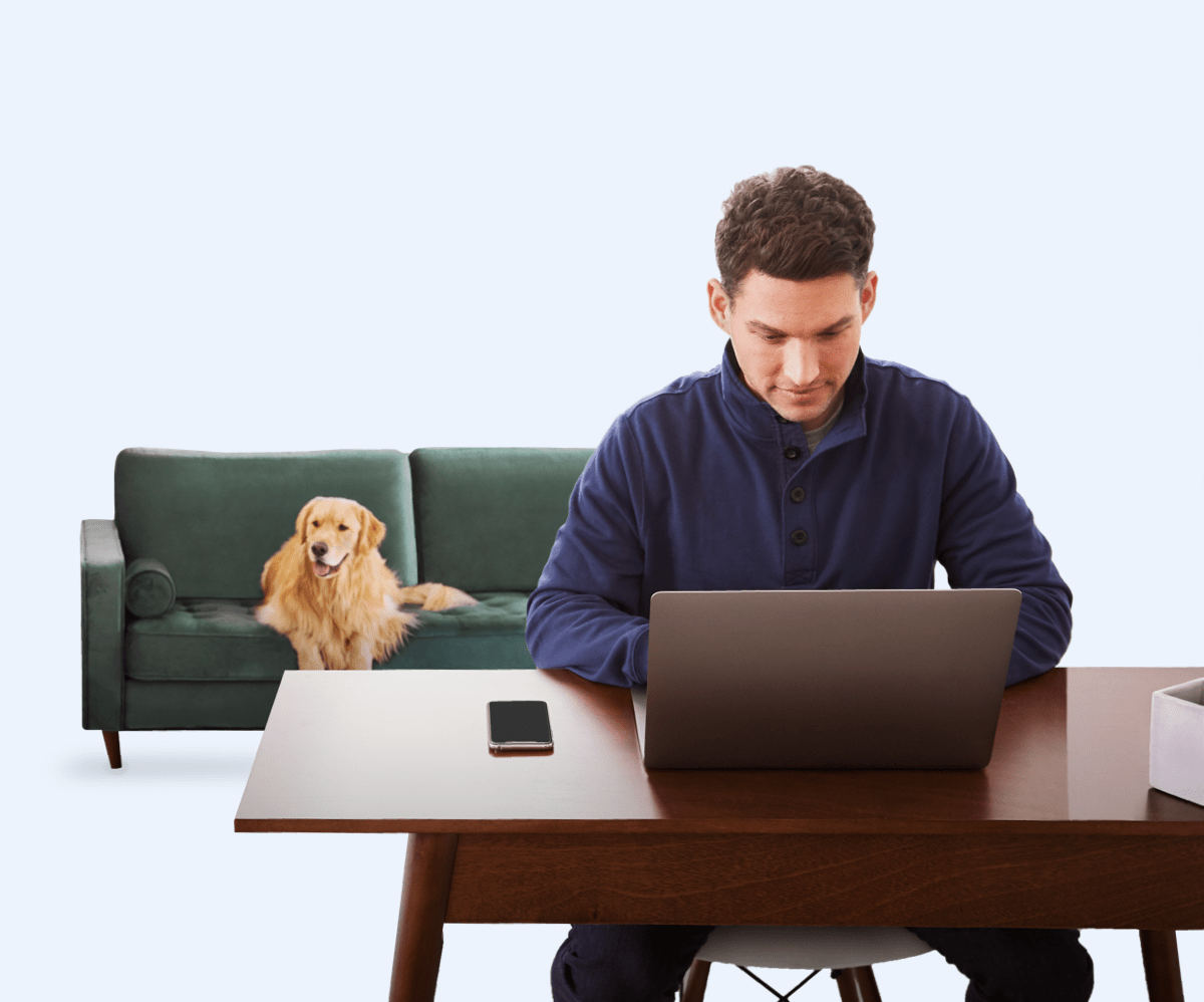 Man sitting at desk, golden retriever sitting on couch behind him