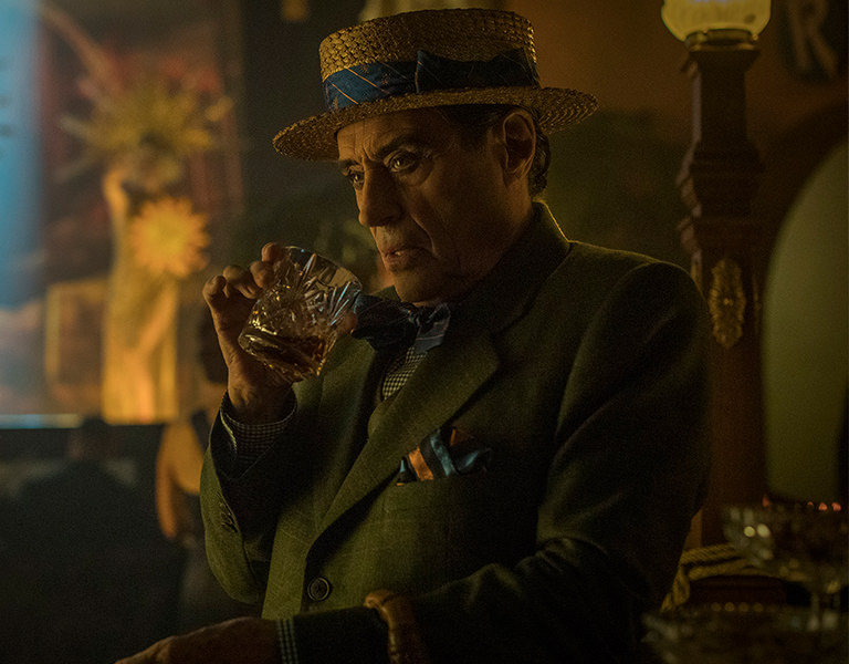 Man in hat sipping a glass of whiskey