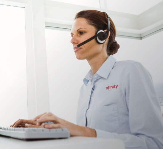 una persona con auriculares, sentada ante una computadora